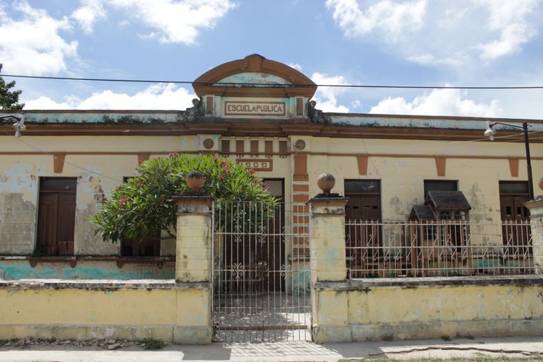 Facade of an old public school in Acanceh, Yucatán, Mexico, showcasing architectural decay.