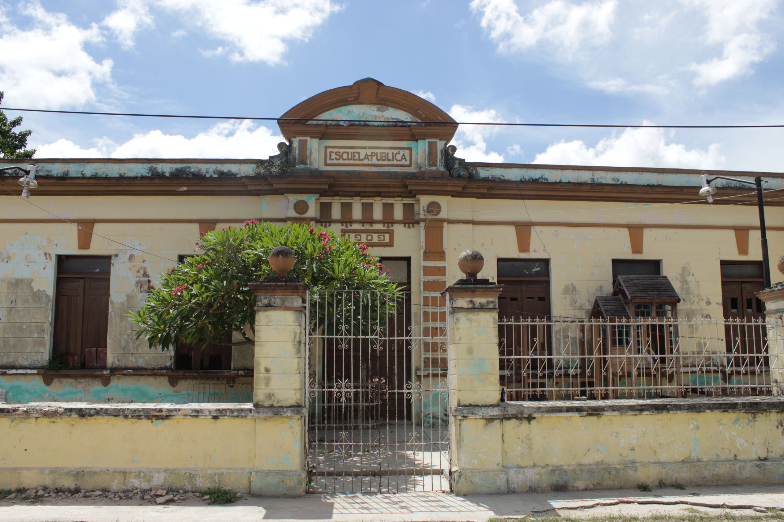Facade of an old public school in Acanceh, Yucatán, Mexico, showcasing architectural decay.